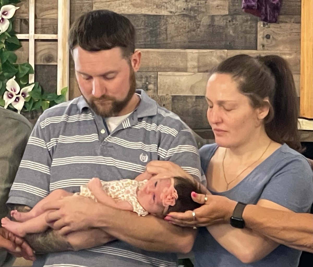 Pastor praying over an infant during a baby dedication service