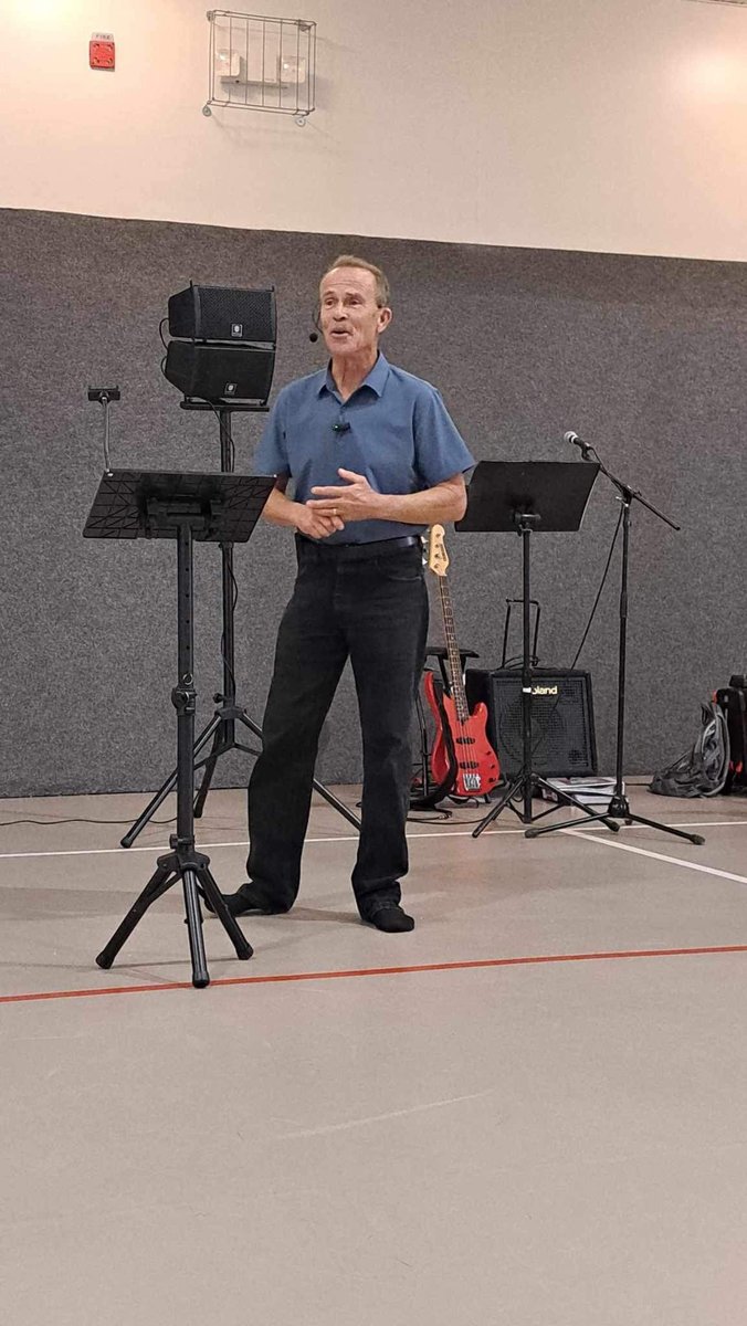 Worship leader singing on stage with a guitar and music stand