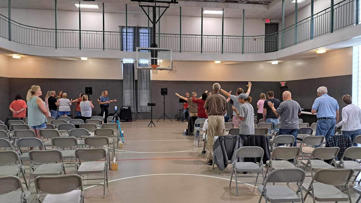 Congregation standing together in worship in the NFM meeting space