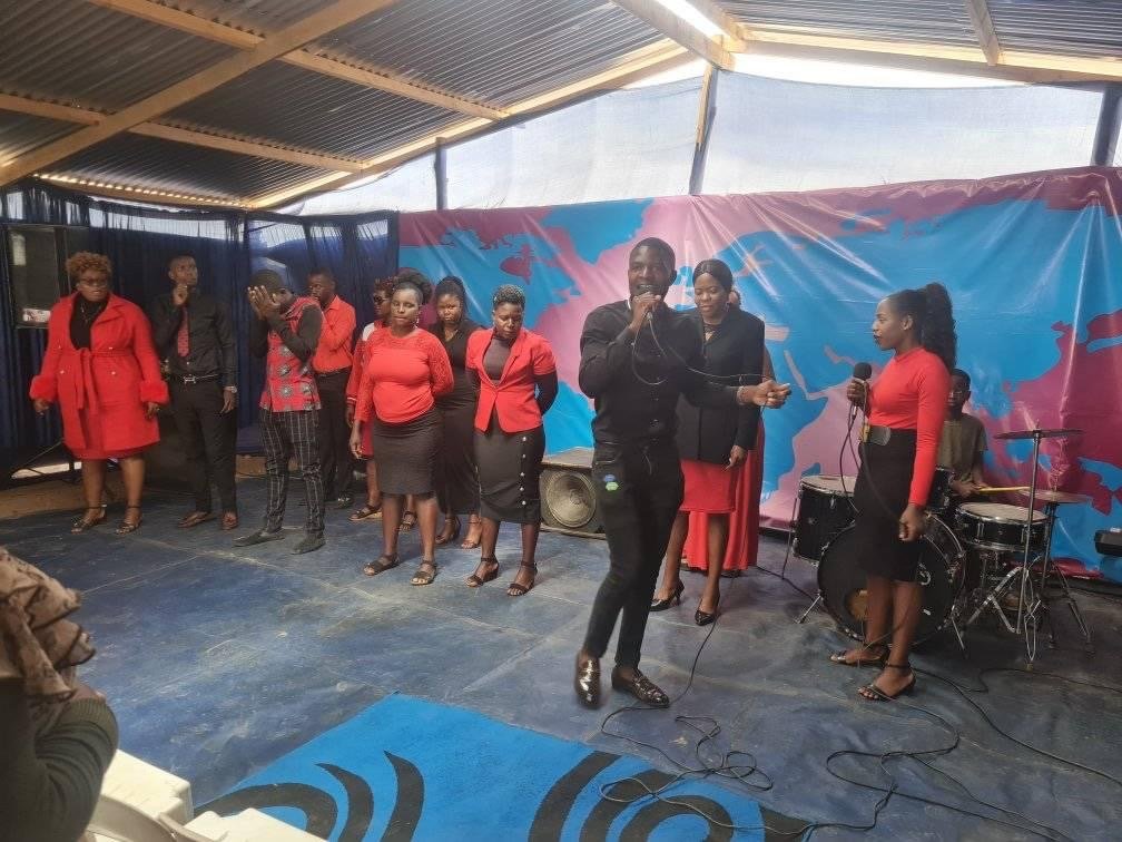 Choir singing on stage in front of the seated Karoi congregation