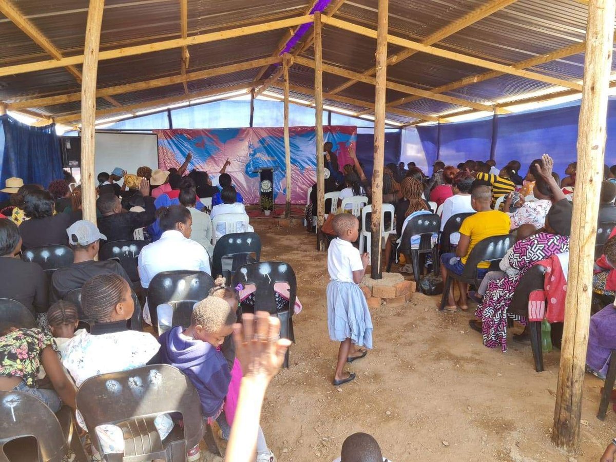 Congregation seated on rows of chairs for the first service in the finished Karoi church