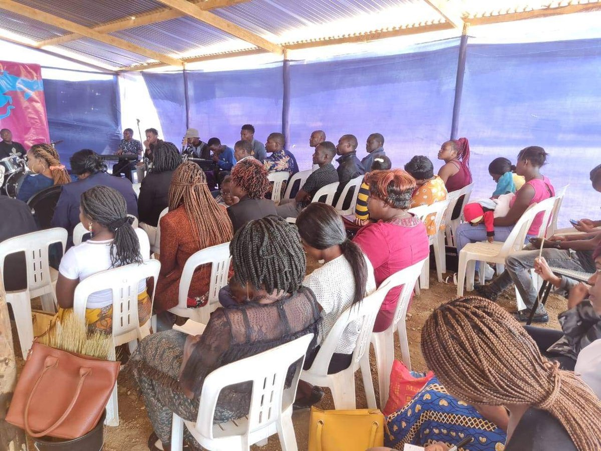 Congregation filling the Karoi church, many with hands raised in worship