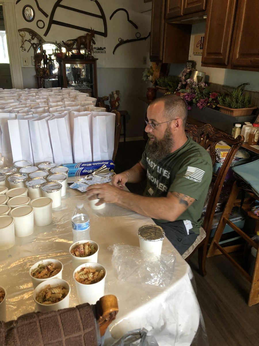Volunteer filling individual meal cups at a prep table