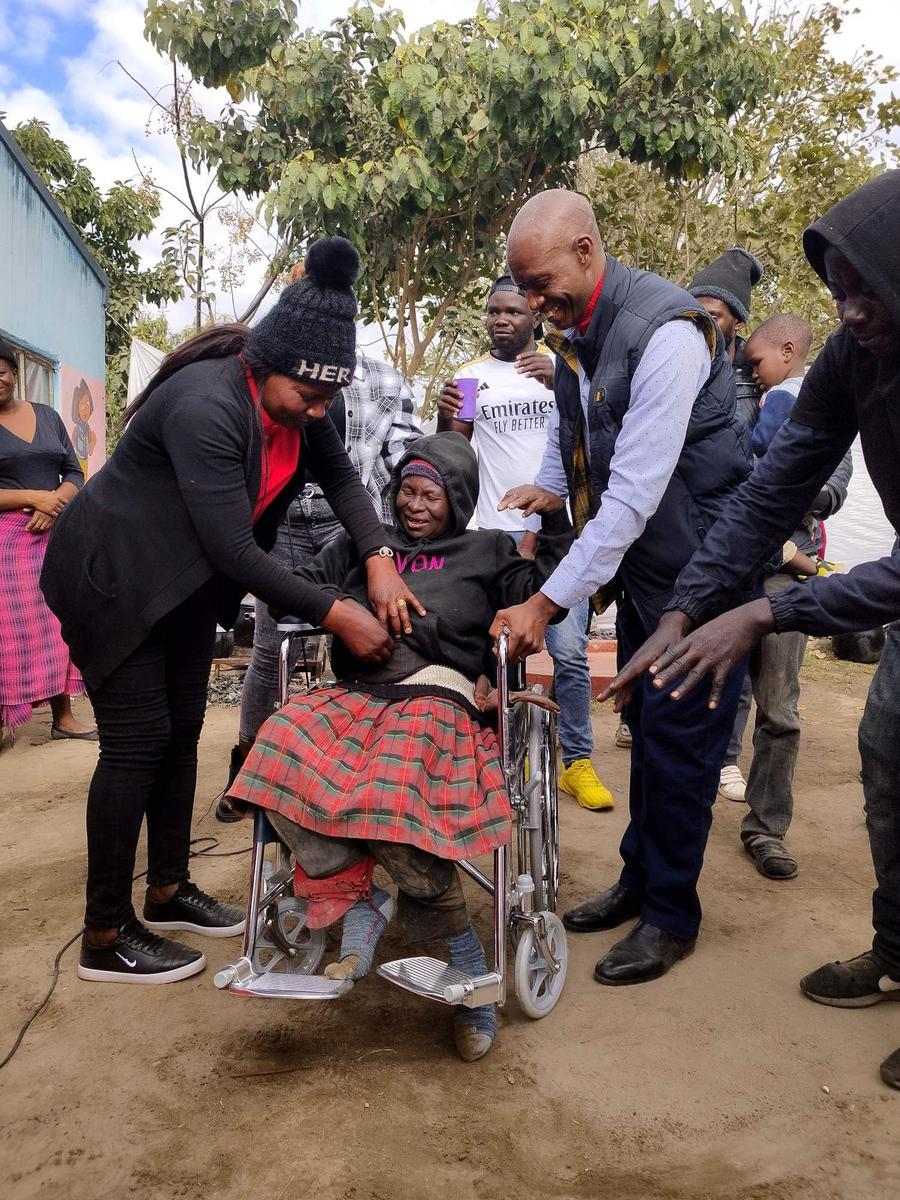 NFM team helping another elderly wheelchair recipient during the visit